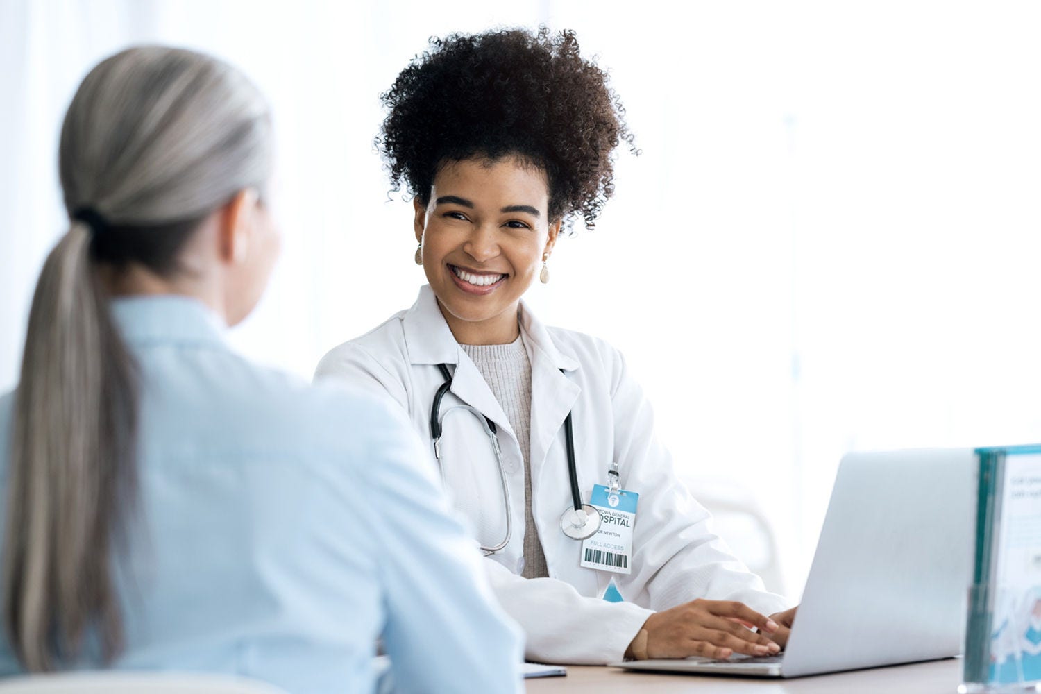 Doctor working on laptop and looking at patient